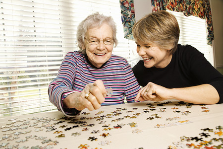 老年妇女和年轻的女人做拼图
