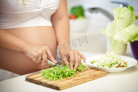 孕妇在木板上切生菜