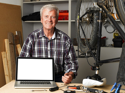 senior bike shop owner behind laptop