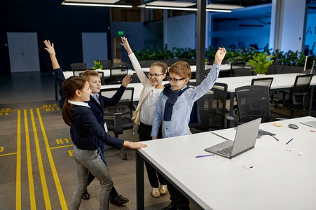 团队举手摄影照片_聪明的孩子举手庆祝成功。小孩子们的商业团队展现了胜利的姿态。聪明的孩子举手庆祝成功