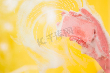 奥林巴斯数码相机.关闭手戴粉红色手套洗涤黄色背景与海绵