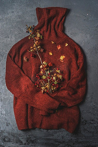 保暖衣服摄影照片_棕色针织羊毛毛衣与秋天分支在黑暗背景。天然材料保暖衣服。俯视图。