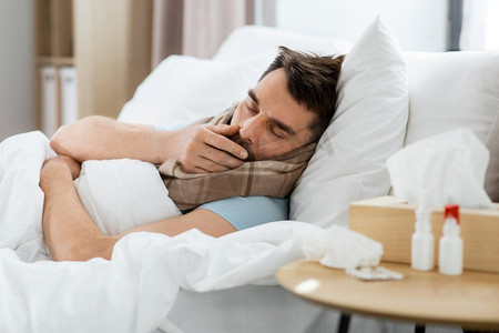 健康与人的概念—生病的男子在家中床上咳嗽。一名病人在家床上咳嗽