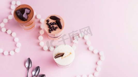 俯视图分层甜点与装饰粉红色背景与项链勺子