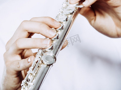 年轻人吹笛子的手。男性长笛演奏家演奏者手持乐器，关闭。手的年轻人吹长笛