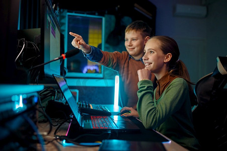 儿童年轻音乐家工作与原声带在计算机坐在录音室的监视器前面。儿童乐队在录音室