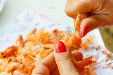 海洋食品摄影照片_海鲜，海洋食品。女性的手在剥生鲜虾。准备做虾..手工去皮生鲜虾。