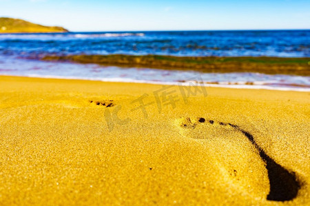 人类的脚摄影照片_人类的脚步在岸上。脚印在沙滩上的沙滩上。旅游，暑假在海滨度假胜地。脚印在沙滩上的沙滩
