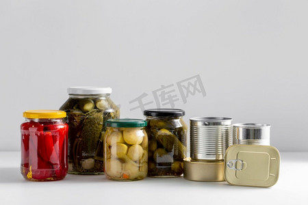 食物，吃和保存概念—罐子和罐头与保存食物在桌子上的特写镜头。近拍的罐子和罐头与腌制食品