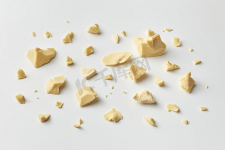 高角度有机纯可可脂块和面包屑放置在白色背景。分散的固体可可油碎片
