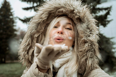 圣诞雪雪摄影照片_女人从她的手吹进雪