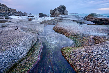 冬日日落时分，挪威海峡湾海滩上的岩石。乌塔克列夫海滩，罗福滕群岛，挪威。挪威峡湾海滩