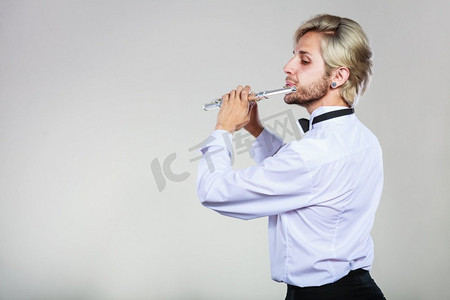 长笛音乐会摄影照片_长笛音乐演奏专业男长笛演奏家。年轻优雅时尚的男子与仪器。他的长笛演奏家