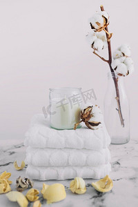 白色蜡烛烛台将白色餐巾堆放在干燥的豆荚附近棉花树枝瓶