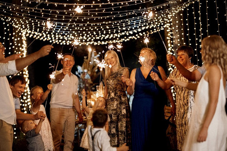 家庭聚餐摄影照片_晚上在森林里用灯泡和蜡烛举行婚礼家庭聚餐