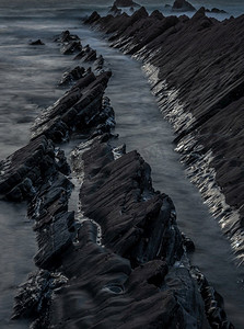 抽象海洋摄影照片_岩石的抽象风景图象在欢迎嘴海滩在日落与潮汐标记在岩石反射阳光