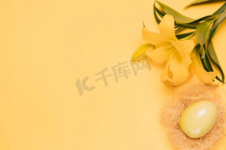 高架视图新鲜百合花与复活节彩蛋巢黄色背景