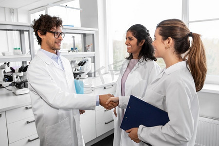 科学、工作和人的概念—快乐科学家在实验室握手的国际小组。科学家在实验室握手