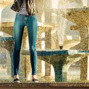 时尚与人的概念。妇女腿牛仔裤休闲风格户外反对城市喷泉