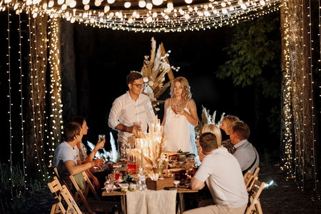 晚上在森林里用灯泡和蜡烛举行婚礼家庭聚餐