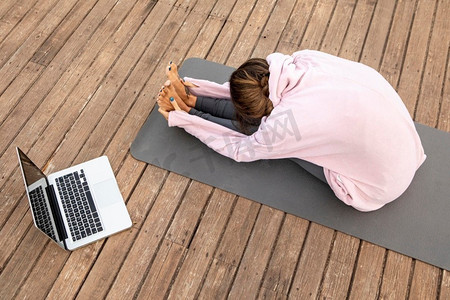 高角度妇女与笔记本电脑做瑜伽户外