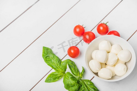 马苏里拉奶酪球，以罗勒叶、红番茄、木白为背景