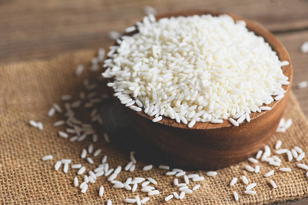 茉莉花白米在木碗和收获的大米袋，收获的大米和食物谷物烹饪概念