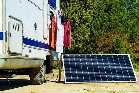 洗衣房和便携式太阳能光伏板，露营车房车充电电池。露营在大自然。大篷车的洗衣房和太阳能电池板