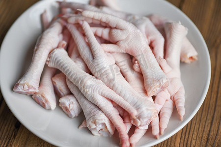 在白色盘子的鸡脚，新鲜的生鸡脚熟的食物在木桌子厨房背景