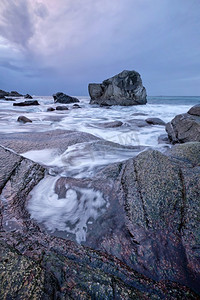 日落时分，冬天的挪威海峡湾海滩上的岩石。乌塔克列夫海滩，罗福滕群岛，挪威。挪威峡湾海滩