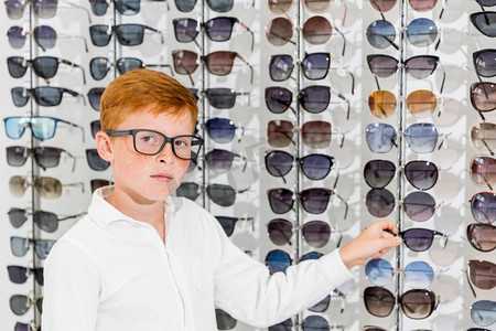 无辜的男孩寻找相机白色举行眼镜光学商店