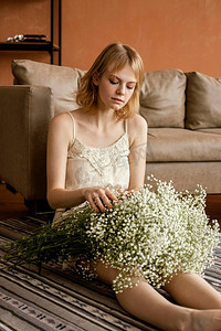 抱着蔬菜摄影照片_娇艳的女人抱着一束娇嫩的春花摆着沙发