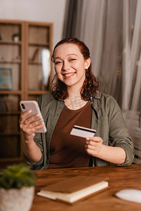 微笑的女人使用信用卡智能手机家