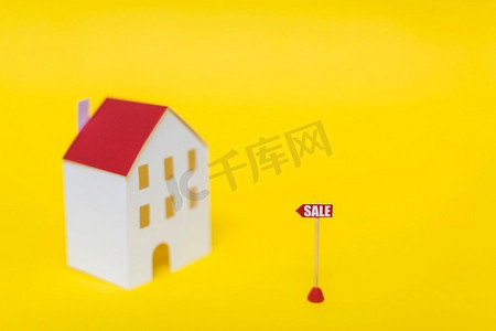 水果标签摄影照片_销售标签前模糊房子模型反对黄色背景