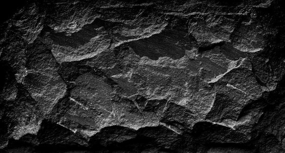 黑色和白色黑暗的石头垃圾背景，岩石墙壁与粗糙的纹理