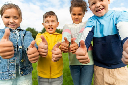 童年、休闲和人的概念-多民族快乐的孩子在公园竖起大拇指。快乐的孩子们在公园竖起大拇指