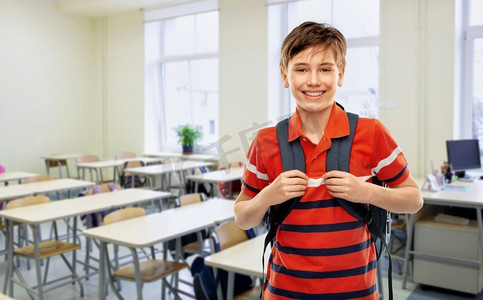 学校，教育和人的概念—微笑的学生男孩有背包在空的教室背景微笑的学生男孩背包在学校