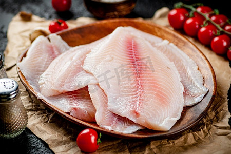 新鲜的鱼片放在木盘子里。黑色背景。高质量的照片。新鲜的鱼片放在木盘子里。 