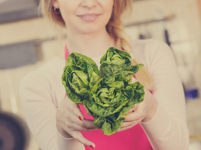 女人，厨师长拿着绿生菜。女性爱蔬菜即将烹饪.. Womna抱着绿色生菜
