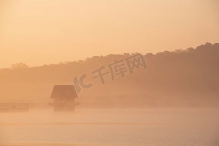 在水库湖上的春天日出的史诗风景图像与黎明的光辉散布在水与低雾添加大气