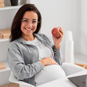 微笑的孕妇抱着苹果回家