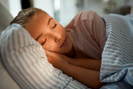 人，就寝时间和休息的概念—女孩睡在家里的床上。女孩睡在床上在家里