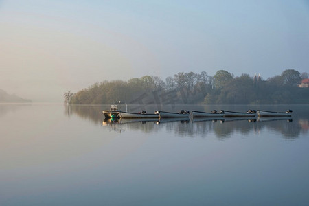 在水库湖上的春天日出的史诗风景图像与黎明的光辉散布在水与低雾添加大气