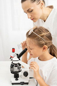 女孩学习看显微镜与女教师