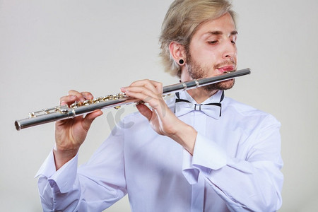 长笛音乐演奏专业男长笛演奏家。年轻优雅时尚的男子与仪器。他的长笛演奏家