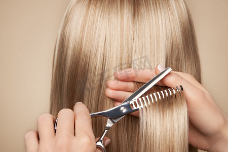 理发师用剪刀剪金色长发。发廊，发型师。护理和美容美发产品。染发