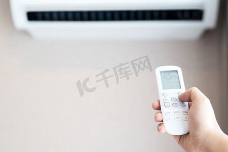 人们拿着遥控空调，25摄氏度的房子里省电。