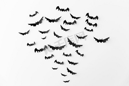万圣节，装饰和可怕的概念-成群的黑色纸蝙蝠在白色背景上飞翔。白色背景上的一群黑色纸蝙蝠