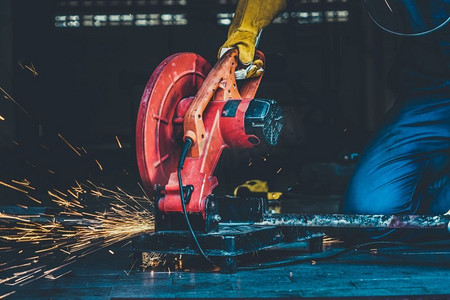 专业的机械师是用旋转金刚石刀片切割钢金属。钢铁工业和车间概念。