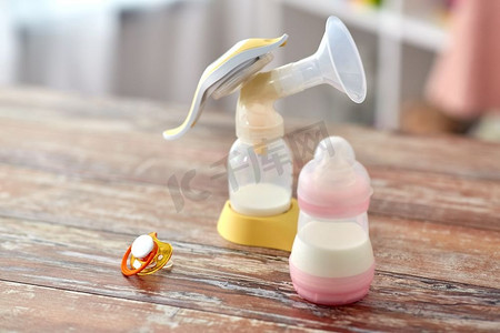 喂养概念—在家里的木桌上放有婴儿配方奶粉、安抚剂和吸奶器。婴儿配方奶瓶和吸奶器